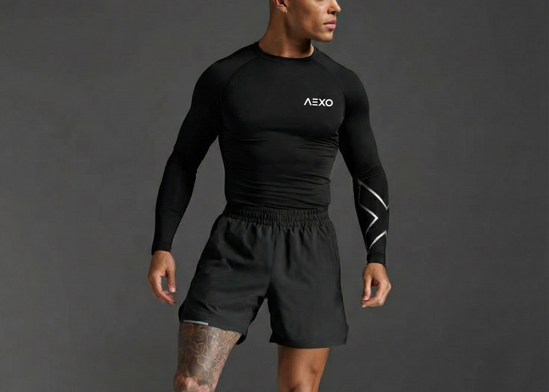 Person wearing black athletic outfit with 'AEXO' branding on a gray background